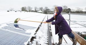Young girl cleaning snow covered solar cells